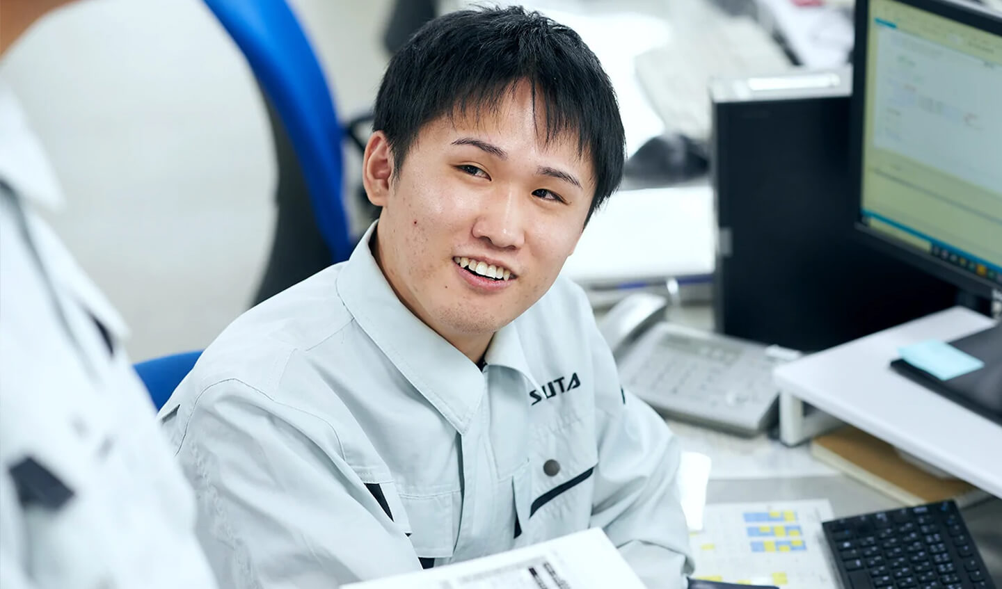 笑顔で同僚と話す情報システム部の社員