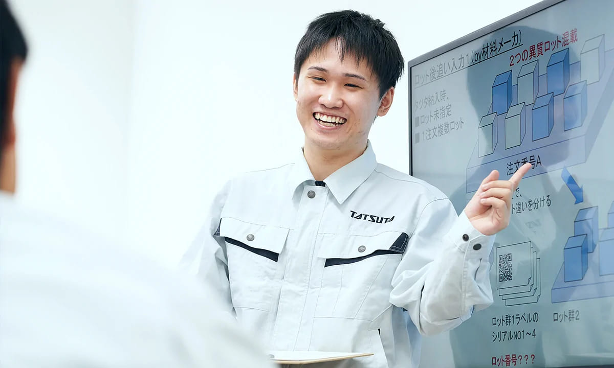 モニターで説明する情報システム部の社員