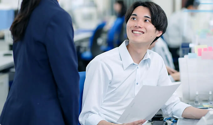 社内で同僚と話す営業部の社員